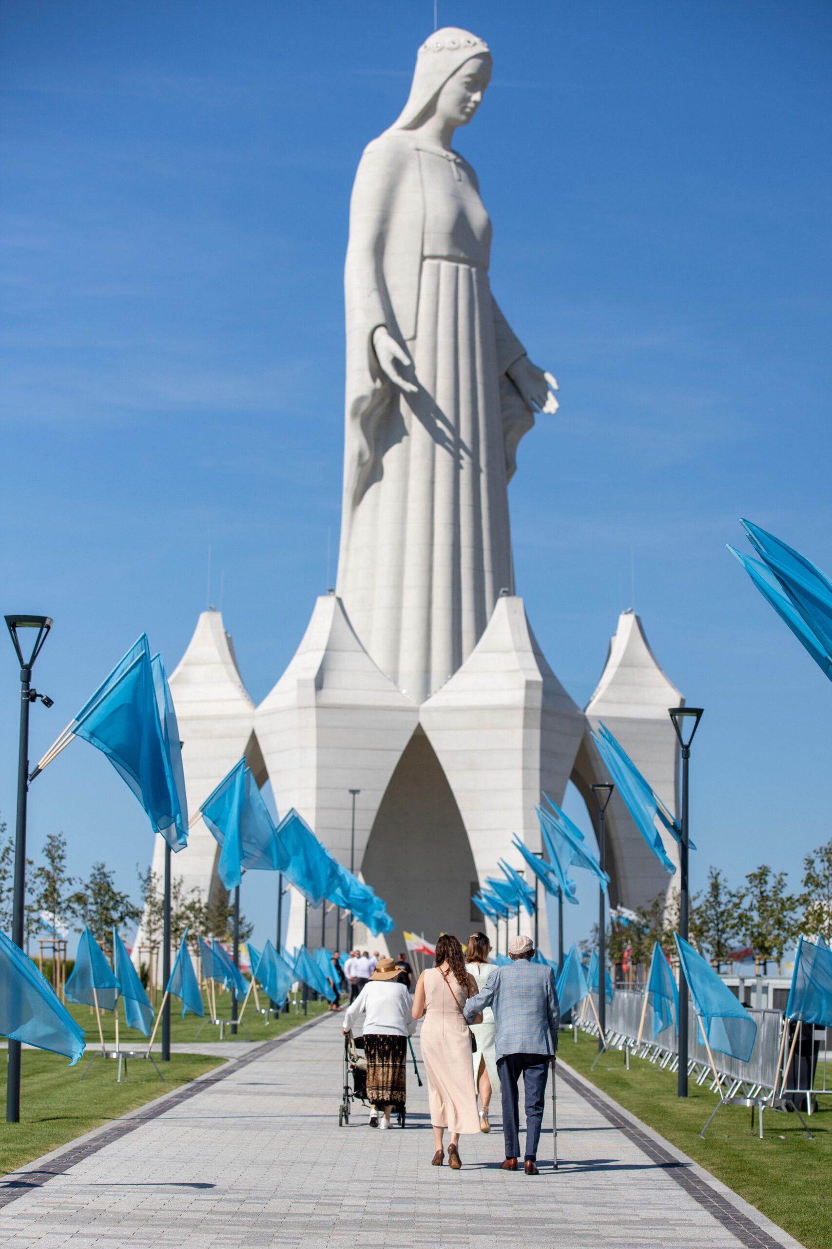 The full height of the statue seen from an approaching vista decked out in blue flags.