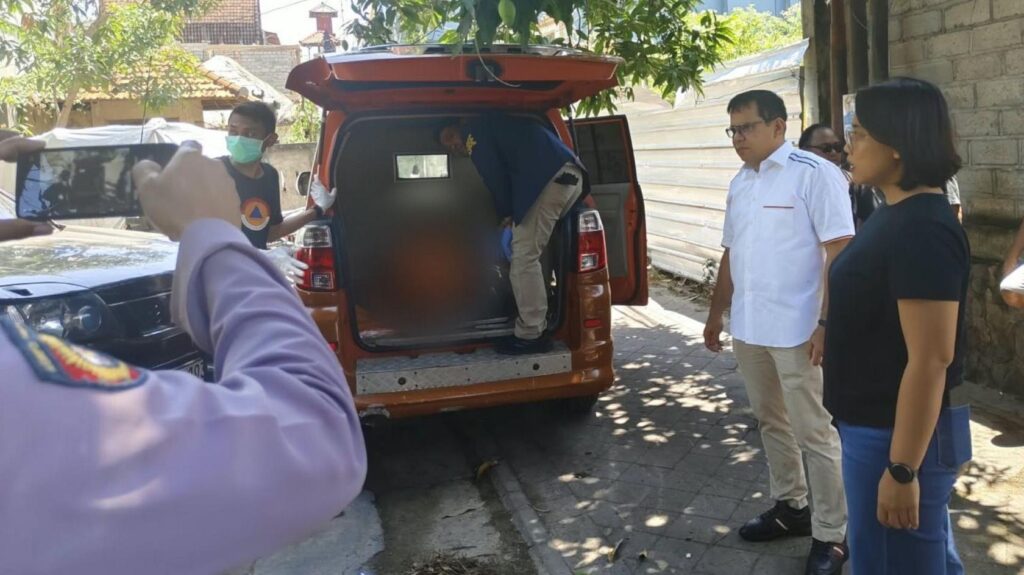 A person stands inside the rear end of an orange van while several other people stand beside the vehicle