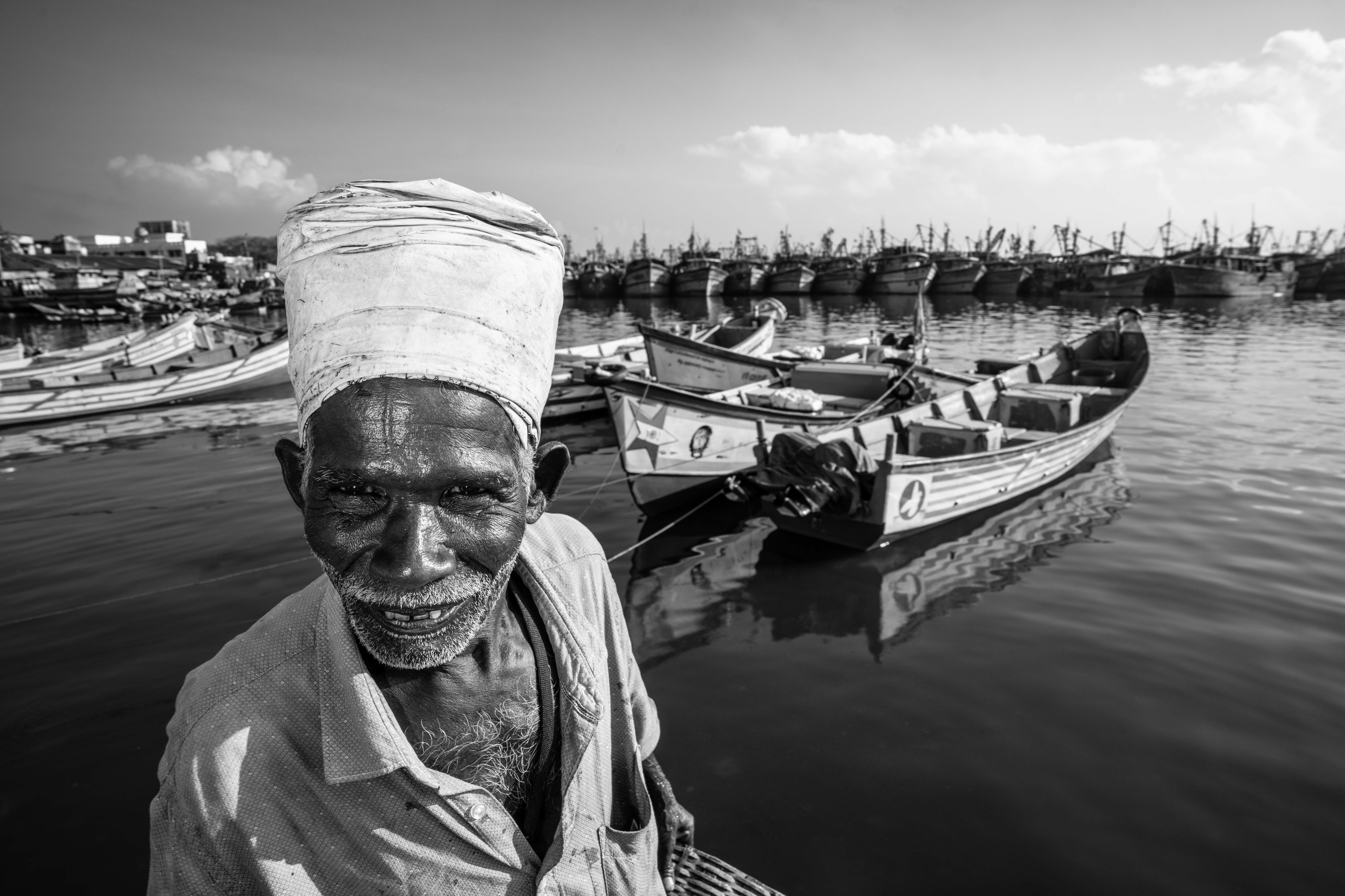 Pavadairayan, 60, a migrant laborer known as a "basket man," carries fish in a basket on his head from boats to the auction house at Kasimedu Fishing Harbour in Chennai, India.
