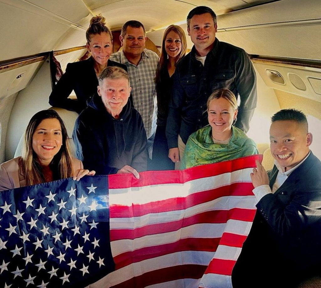 Stephen Hubbard (second from left in the first row) poses with family members and American officials on board a flight to the US after his release from prison. Photo: 21 October 2026