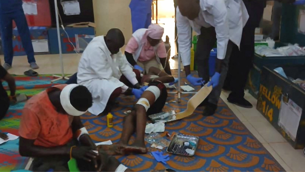 Medical workers - two men in white coats and a nurse in a pink uniform - treat injured people at Ameth Bek Hospital on the floor after a drone strike on a market in the disputed Abyei region along the border between South Sudan and Sudan, 19 October 2026.