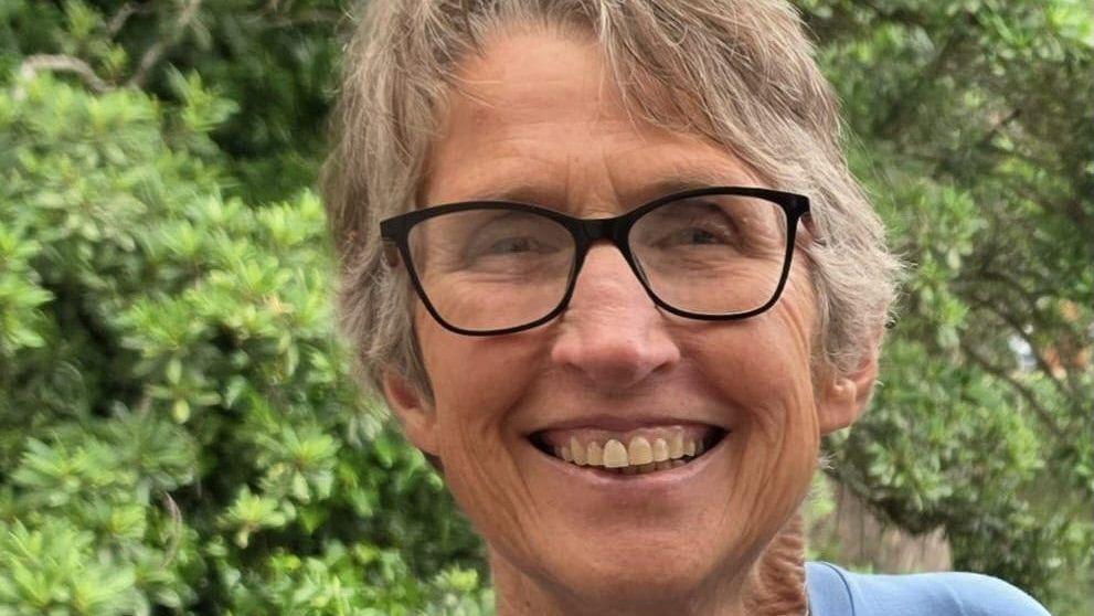 Janine Lochrenberg, 65, is seen smiling as she poses in front of some trees