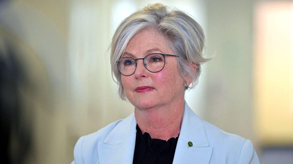 Head and shoulders crop of a portrait of Helen Haines wearing glasses with light cropped hair while wearing a black top and cream blazer, sitting indoors with a bokeh background at Parliament House in Canberra in September.